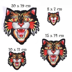 May include: Embroidered patches featuring a snarling tiger face in shades of black, orange, red, and yellow. The patches vary in size, with the largest measuring 20 cm x 19 cm and the smallest 8 cm x 7 cm. The tiger's mouth is open, revealing white teeth.