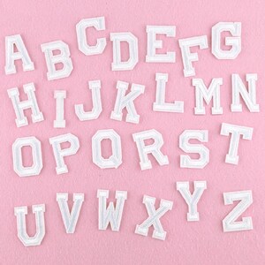 Peut inclure: Lettres de l'alphabet en feutre blanc, de A à Z, sur un fond rose.