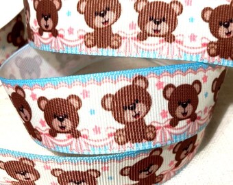 May include: White ribbon with a repeating pattern of brown teddy bears, pink stars, and blue and pink bows. The ribbon has a light blue border.