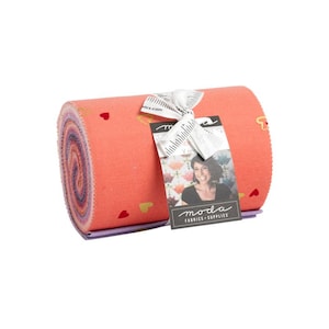 May include: A roll of fabric with a pink and purple ombre pattern and small red and gold hearts printed on the fabric. The fabric is tied with a white ribbon and a tag that says "moda fabrics-supplies".