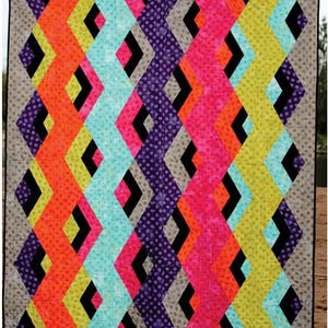 May include: A colorful quilt titled "Tidal Pool" with a geometric design. The quilt features zig-zag patterns in vibrant colors like orange, pink, teal, purple, and yellow, separated by black diamond shapes. The quilt is framed with a gray border and the "Swirly Girls" logo.