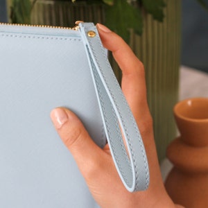 May include: A light blue clutch purse with a gold zipper and a matching light blue wrist strap.