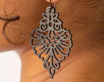 May include: A pair of silver filigree earrings with a delicate, intricate design. The earrings are shaped like a teardrop and have a dangling, ornate pattern.