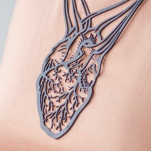 May include: A black anatomical heart necklace with intricate details. The necklace is made of a lightweight material and features a delicate chain.
