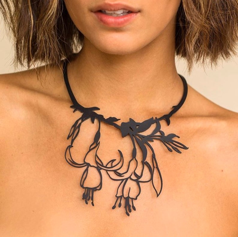May include: A black necklace with a delicate floral design. The necklace is made of metal and features a cluster of stylised flowers.