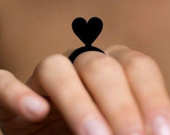 May include: A black heart-shaped ring worn on a finger.