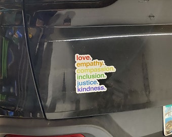 May include: A black car bumper with a rainbow sticker that reads "love, empathy, compassion, inclusion, justice, kindness."
