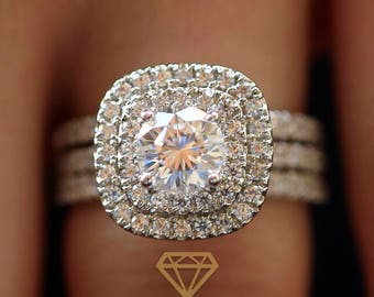May include: A silver engagement ring with a large, round, clear diamond center stone surrounded by two rows of smaller diamonds. The ring has a double band with a row of smaller diamonds on each band.