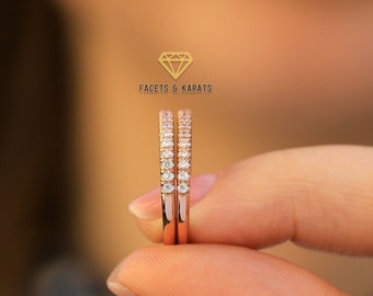 May include: Two delicate rose gold rings with a row of small diamonds on each band. The rings are held in a hand, with the text "Facets & Karats" visible in the background.