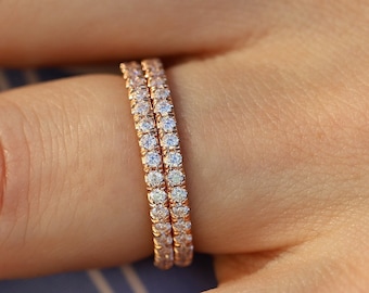 May include: Two rose gold eternity bands with a row of small round diamonds set in each band.