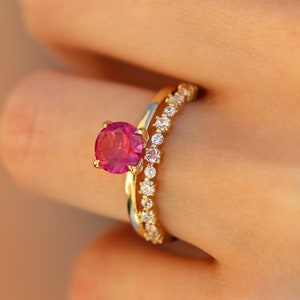 May include: A gold ring with a pink gemstone and a matching band of smaller diamonds.