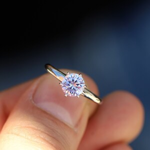 Puede incluir: Un anillo de plata con un solo diamante redondo y transparente.