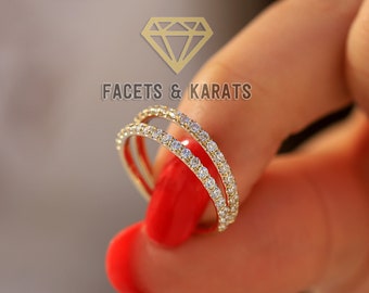 May include: A delicate gold ring with two rows of sparkling diamonds. The ring is set on a finger with red nail polish.