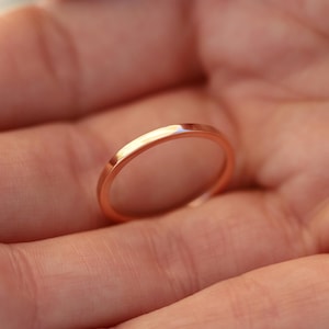 May include: A thin rose gold band ring. The ring is simple and elegant, perfect for a minimalist look.