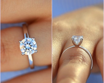 May include: A silver solitaire engagement ring with a round brilliant cut diamond.