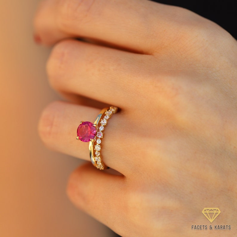 May include: A gold ring with a pink gemstone and a matching band of smaller diamonds.