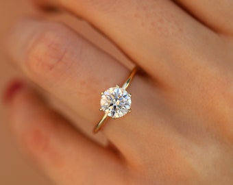 May include: A gold engagement ring with a large, round, clear diamond.