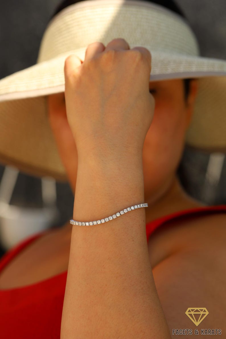 May include: A woman's wrist wearing a silver tennis bracelet with small, clear diamonds.