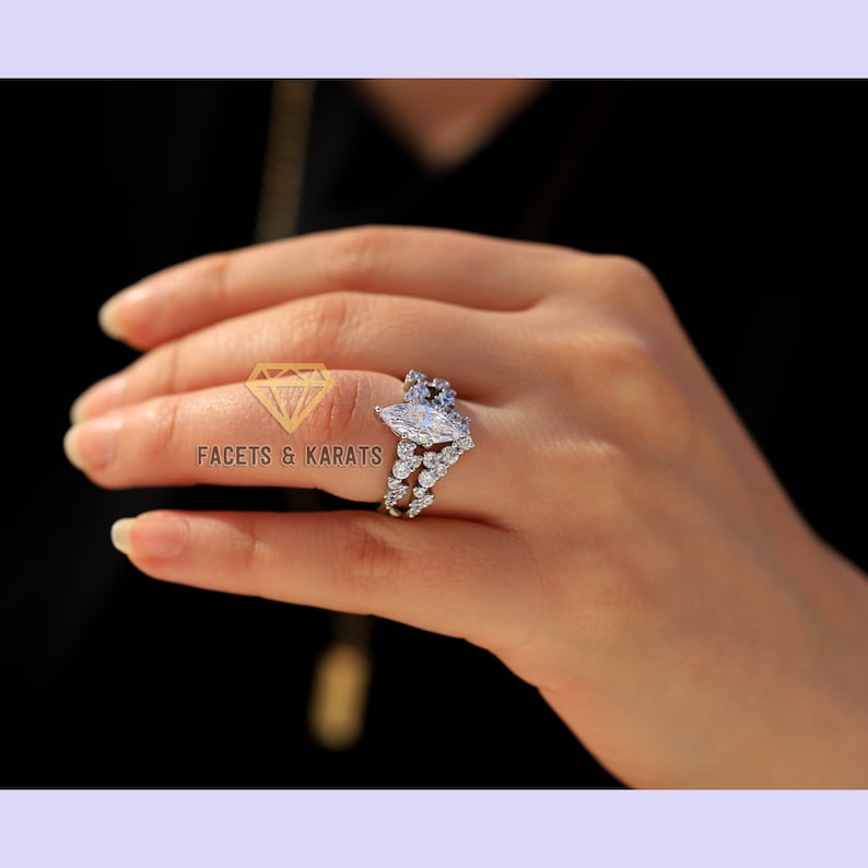 May include: A silver ring with a large marquise-shaped diamond surrounded by smaller diamonds. The ring is set on a band with a delicate design.