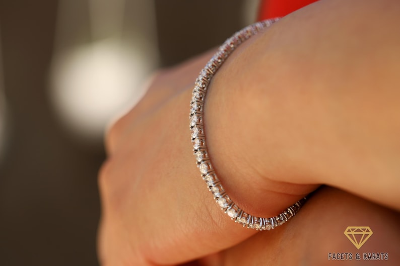 May include: A silver tennis bracelet with a row of small, clear diamonds.