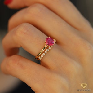May include: A gold ring set with a large, oval-shaped pink gemstone and a smaller band of pave-set diamonds.