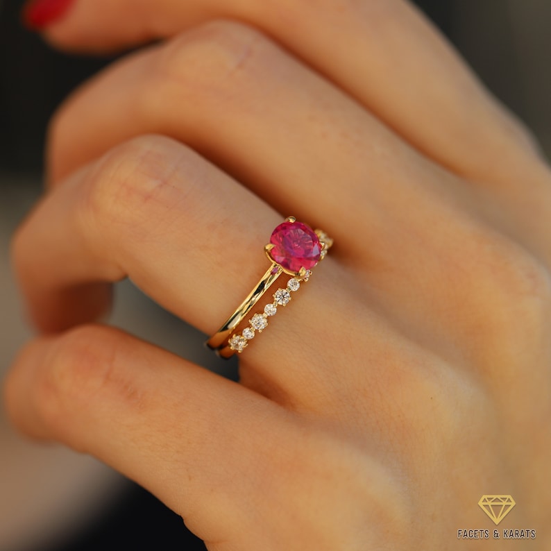 May include: A gold ring set with a large, oval-shaped pink gemstone and a smaller band of pave-set diamonds.