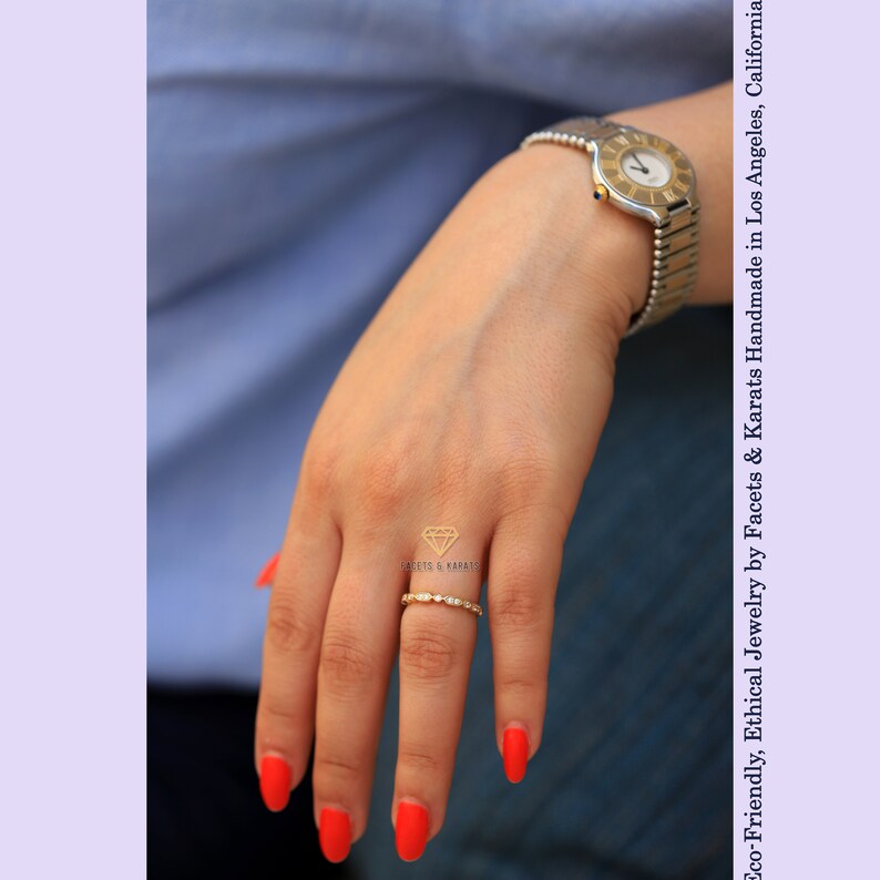 Op de afbeelding: Een gouden ring met kleine ronde diamanten in een pav&eacute;-setting. De ring zit aan een vinger met rode nagellak.