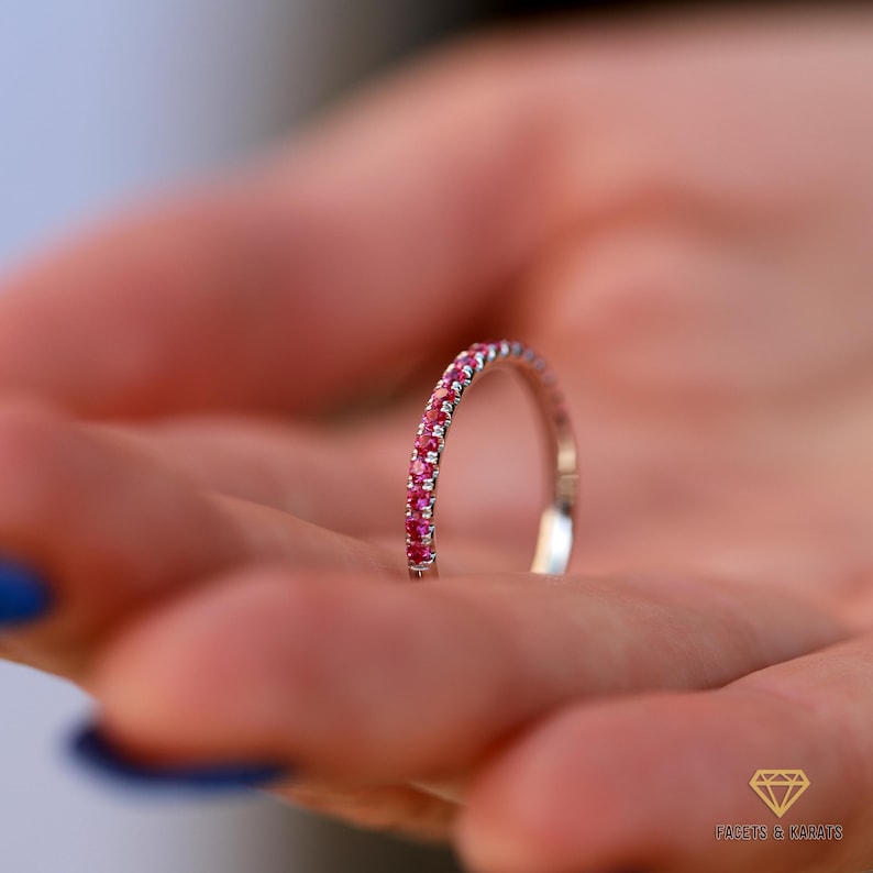 Half eternity ruby wedding band for women with 1.5mm stones being held by a model, made in platinum by Facets and Karats
