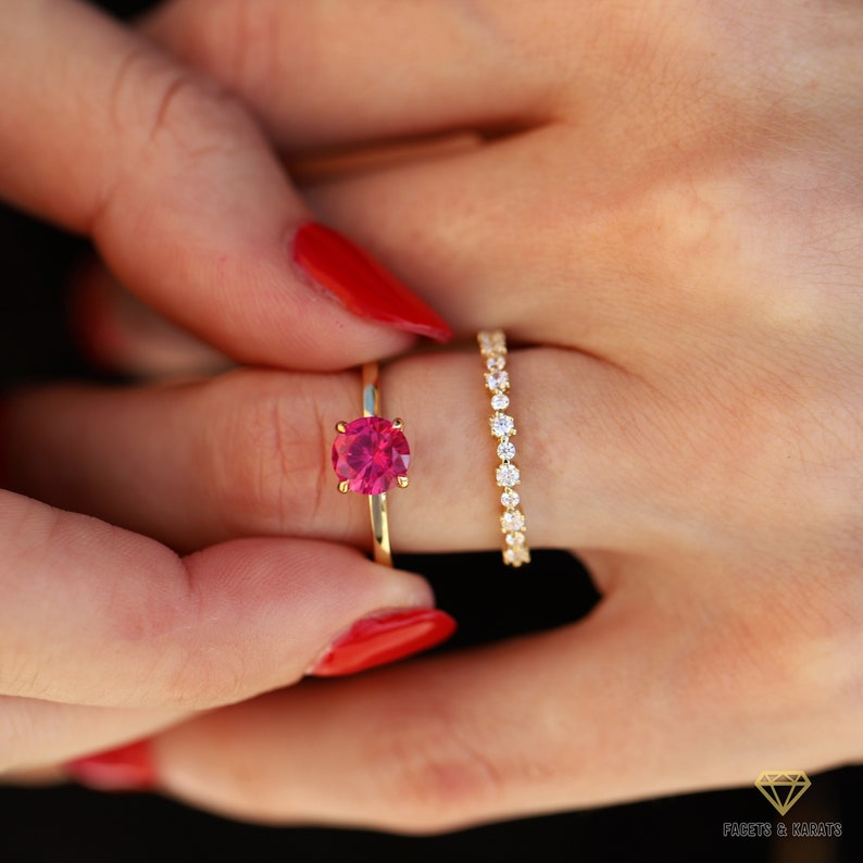 May include: A gold ring featuring a pink gemstone and a gold band with a row of small diamonds.