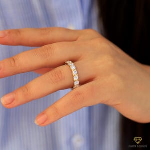 Op de afbeelding: Een gouden ring met een rij ronde, heldere edelstenen.