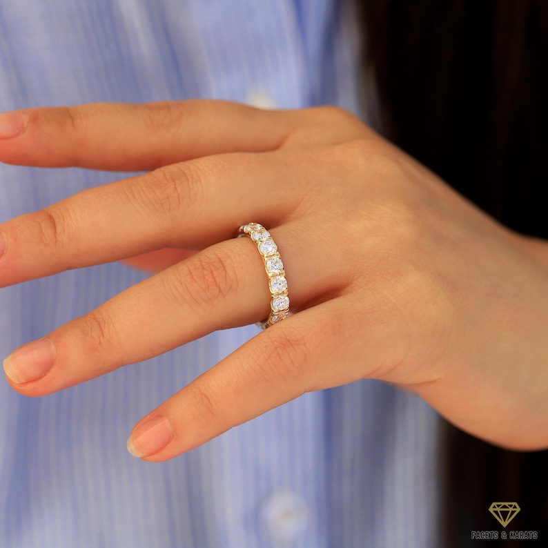 Op de afbeelding: Een gouden ring met een rij ronde, heldere edelstenen.