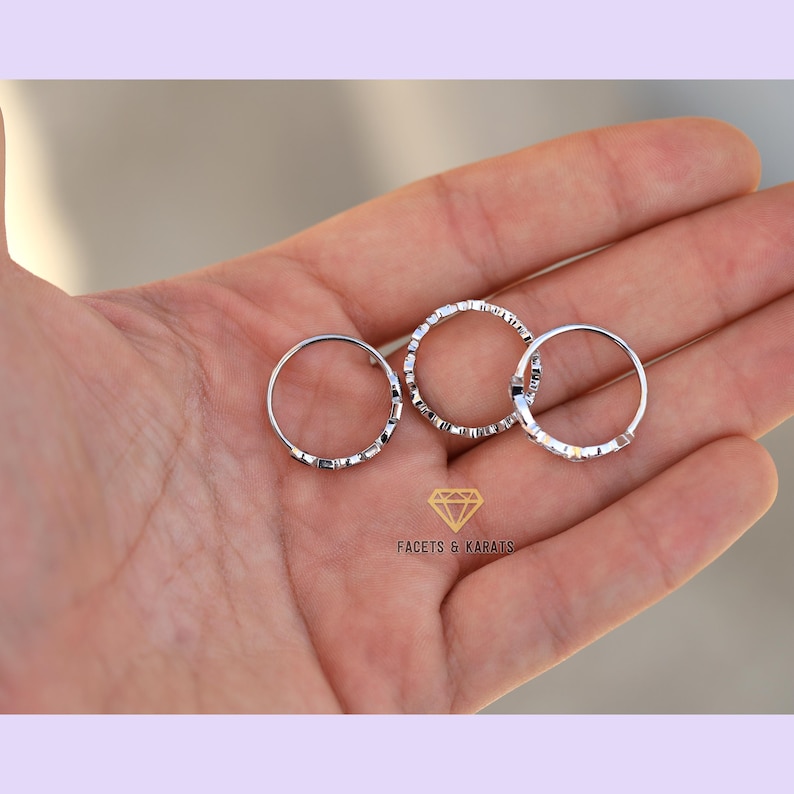 May include: Three silver rings with a textured design. The rings are stacked on top of each other.