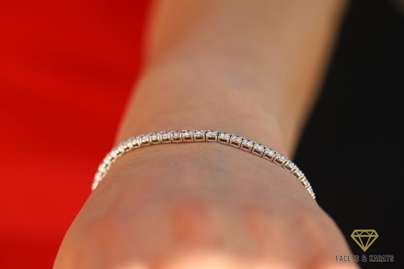 May include: A silver tennis bracelet with small round diamonds set in a continuous line.