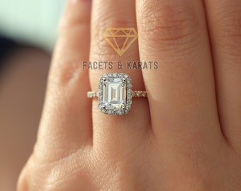 Puede incluir: Un anillo de compromiso de oro con un gran diamante central de talla esmeralda y un halo de diamantes más pequeños. El anillo está engastado en una banda fina con un engaste pavé de diamantes más pequeños.