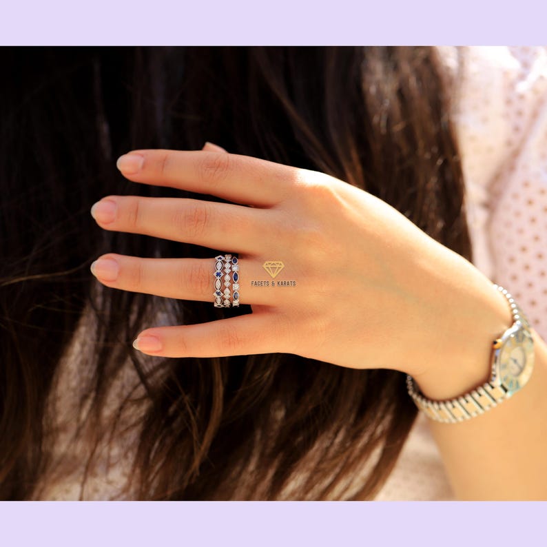 May include: Three gold rings with blue and white gemstones. The rings are stacked on a finger. The text "FACETS & KARATS" is visible in the image.