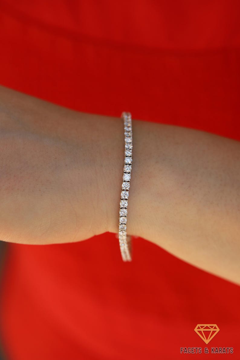 May include: A silver tennis bracelet with a row of clear round stones.