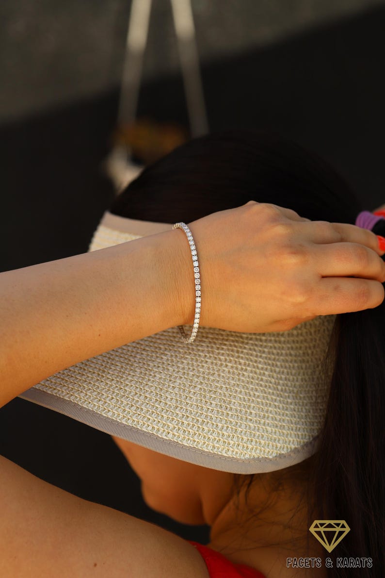 May include: A silver tennis bracelet with small round diamonds set in a continuous line.