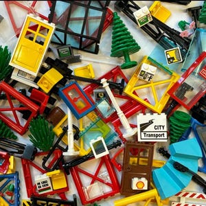 May include: A collection of colorful toy building blocks, including red, yellow, and blue pieces. The image features various shapes like doors, windows, and trees, with a "CITY Transport" sign. A fun assortment of construction toys.