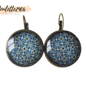 Peut inclure: Une paire de boucles d'oreilles en bronze avec un motif bleu et blanc. Les boucles d'oreilles sont rondes et ont une fermeture à crochet.