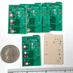 May include: Several green circuit boards with various components, including resistors and connectors. Each board has the text "ESC-1 94V-0 1222" and other markings. A quarter and a ruler with inch measurements are also present.