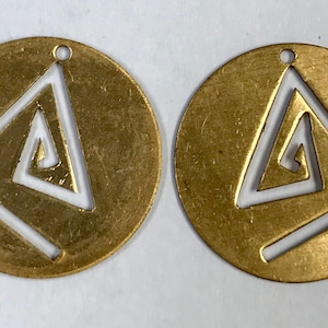 Könnte beinhalten: Zwei messingfarbene, kreisförmige Anhänger mit geometrischem Design. Jeder Anhänger hat ein ausgeschnittenes Dreieck mit einer Innenspirale. Die Anhänger haben kleine Löcher oben zum Aufhängen.