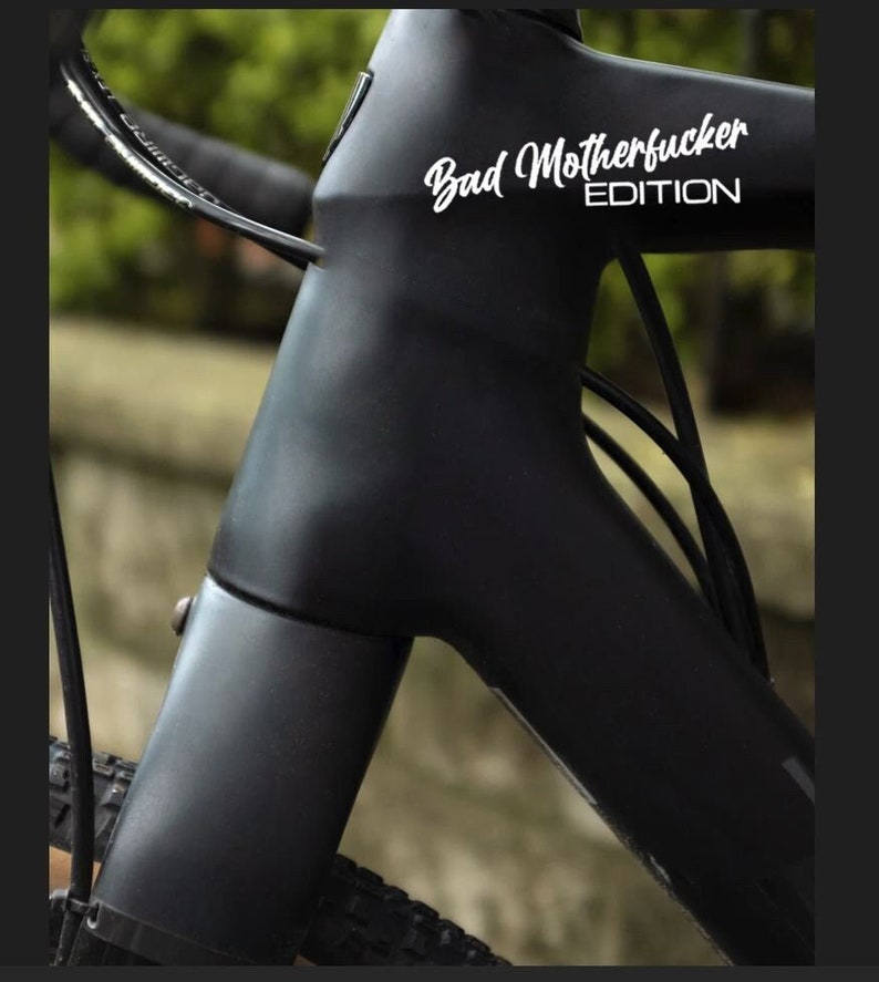 Puede incluir: Un cuadro de bicicleta negro con una pegatina blanca que dice "Bad Motherfucker EDITION".