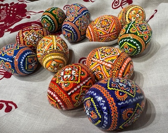 Könnte beinhalten: Eine Sammlung kunstvoll bemalter Ostereier mit geometrischen Mustern in Blautönen, Grün, Orange, Gelb und Weiß.