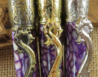 May include: Three purple and white patterned pens with gold and silver dragon-shaped handles. The pens have ornate metal caps with intricate designs.