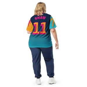 May include: A teal, blue, and yellow jersey with the name "SHAW" and the number "11" printed on the back. The jersey has a tropical print design.