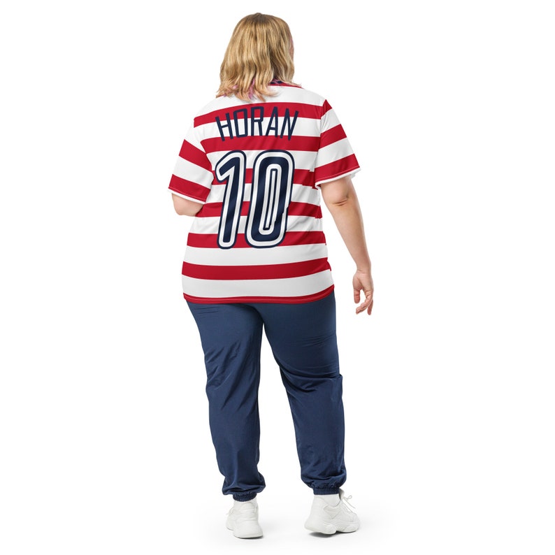 May include: A red and white striped soccer jersey with the name "HORAN" and the number "10" on the back. The jersey is being worn by a person with blonde hair.