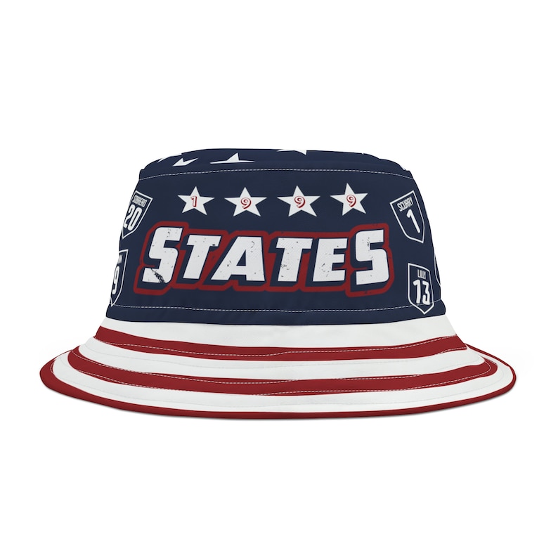 May include: A blue and red bucket hat with a white star pattern and the word "STATES" in white letters with a red outline. The hat also has several small patches with numbers and the word "SCORE" on them.