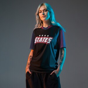 May include: A black and blue jersey with red and white accents. The jersey has a V-neck and the text "STATES" with five stars above it.