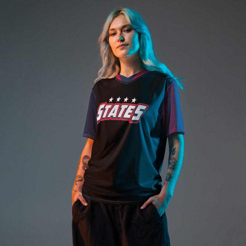 May include: A black and blue jersey with red and white accents. The jersey has a V-neck and the text "STATES" with five stars above it.