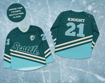 May include: Two teal and light blue Seattle PWHL hockey jerseys. One jersey displays the number 1 and the word "Seattle" in white script. The other jersey shows the name "KNIGHT" and the number 21. The jerseys have white and teal stripes.